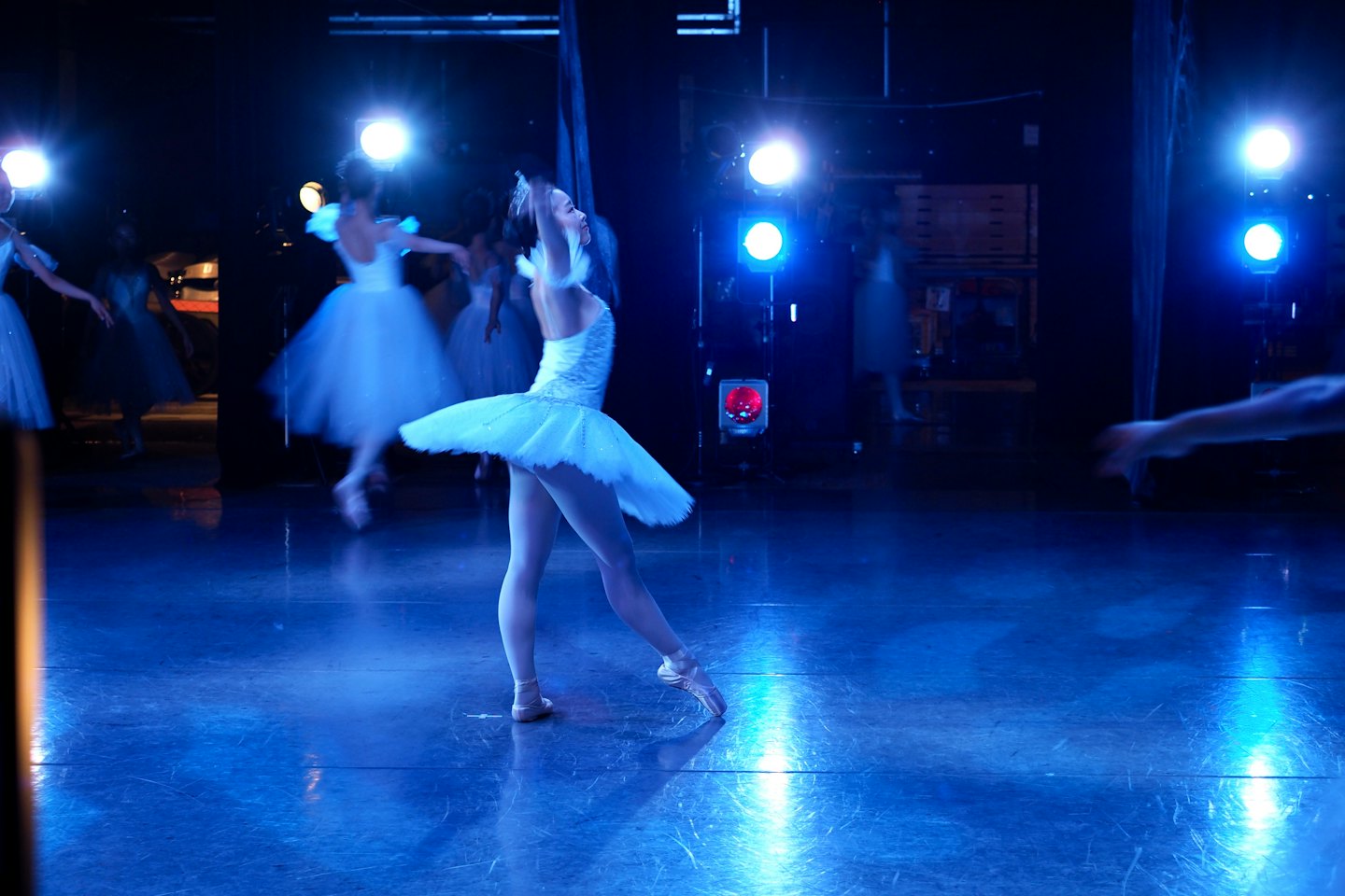 Ballerini di danza classica eseguono mosse aggraziate su un palco buio.