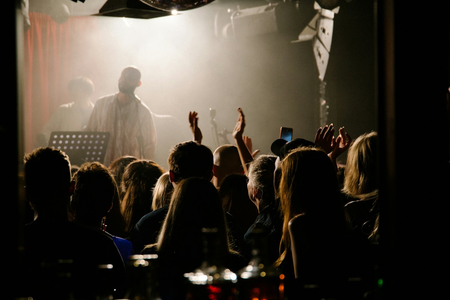 Il pubblico di un concerto tende le mani verso un artista sul palco.