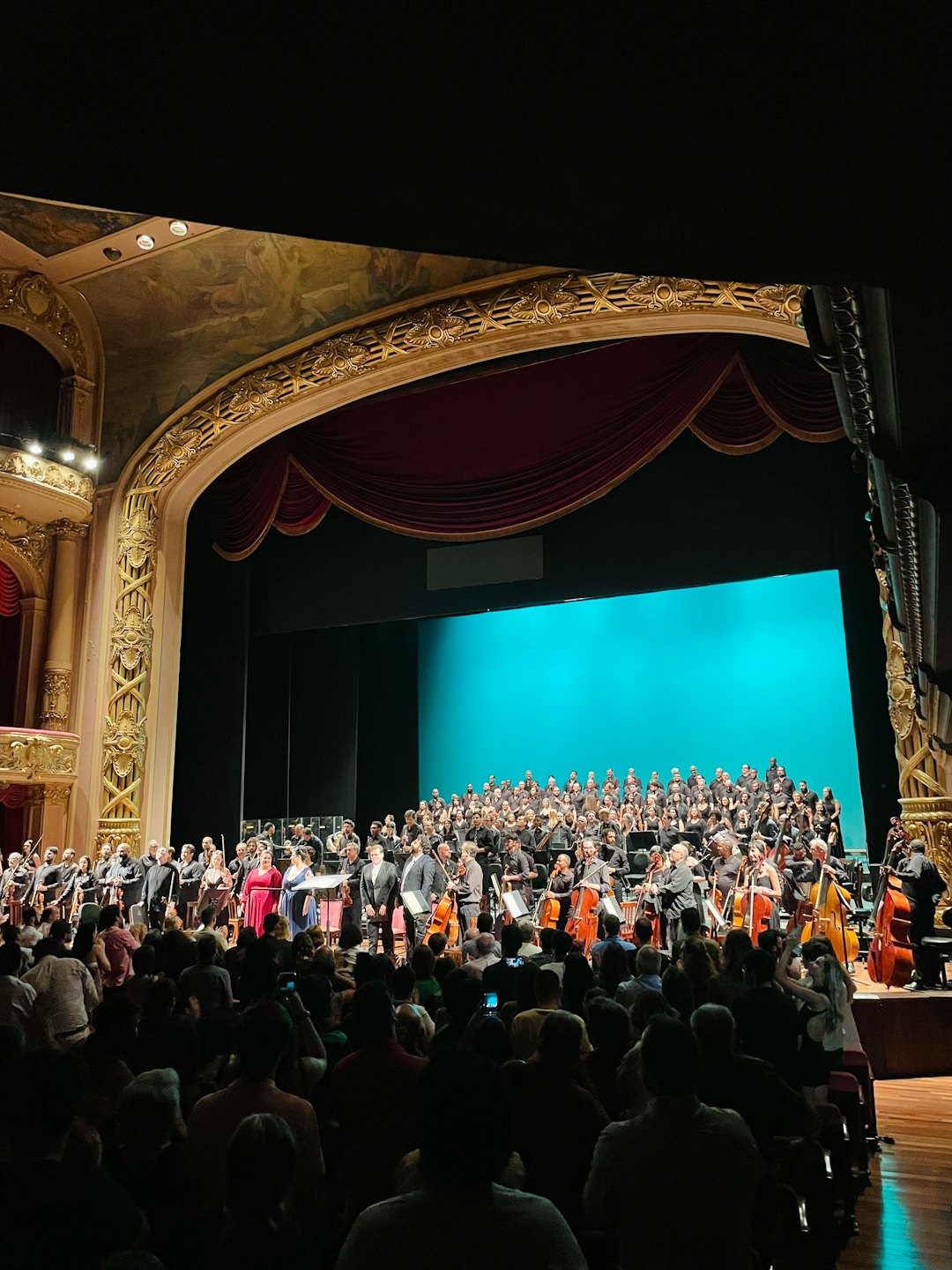 Un'orchestra e un coro si esibiscono sul palco di un grande teatro.