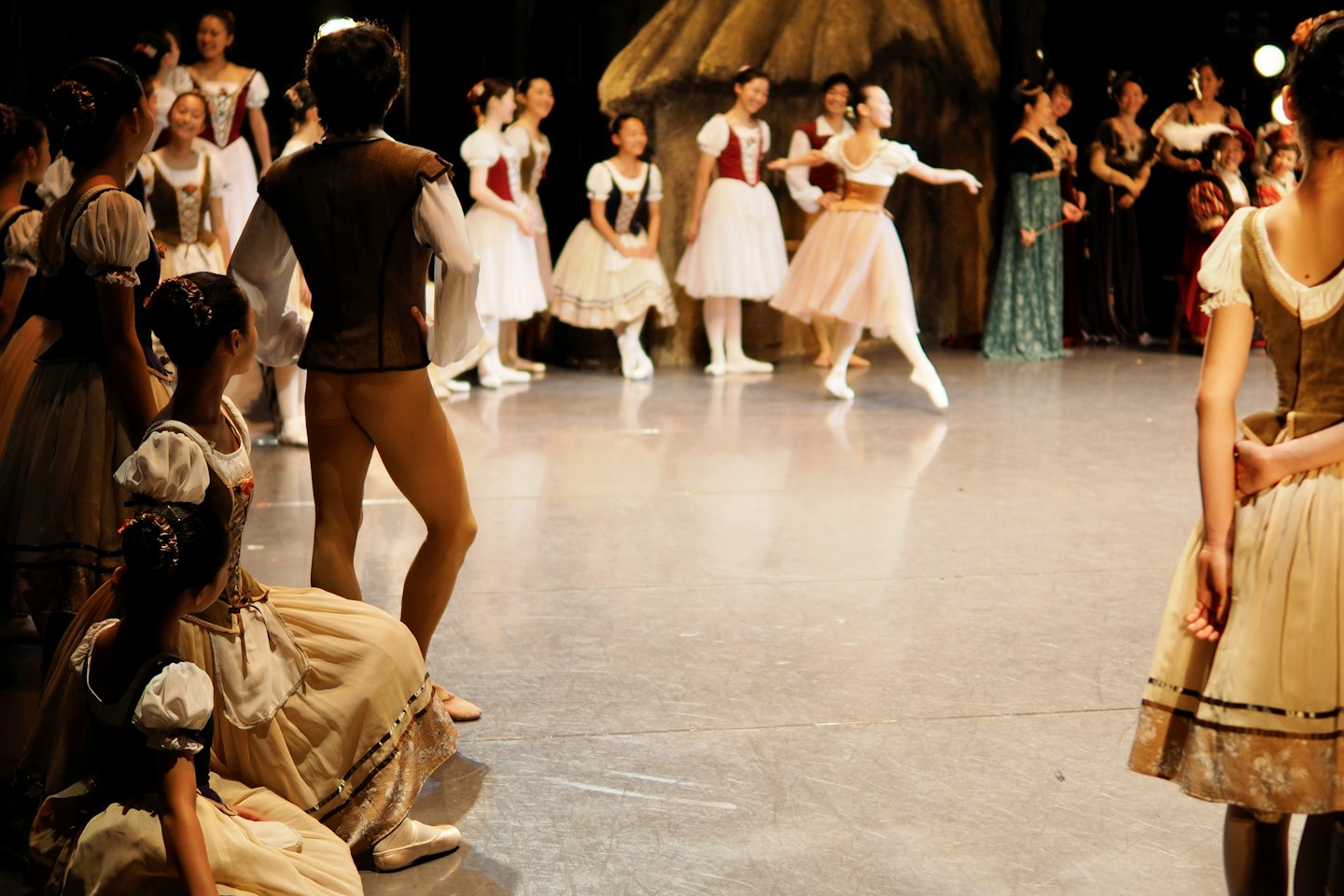 Ballerine in costumi classici su un palco poco illuminato.
