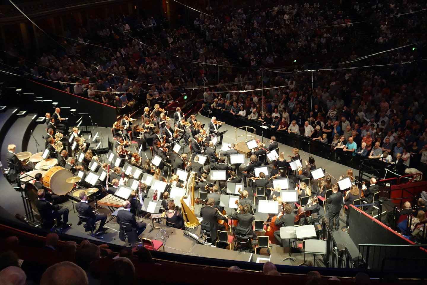 Una grande orchestra si esibisce sul palco per un pubblico seduto.