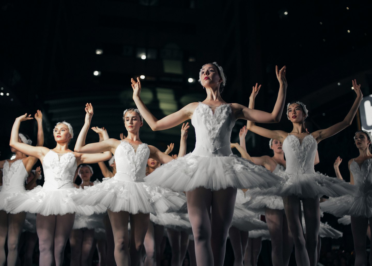 Ballerine diverse si esibiscono con grazia su un palco in tutù bianchi.