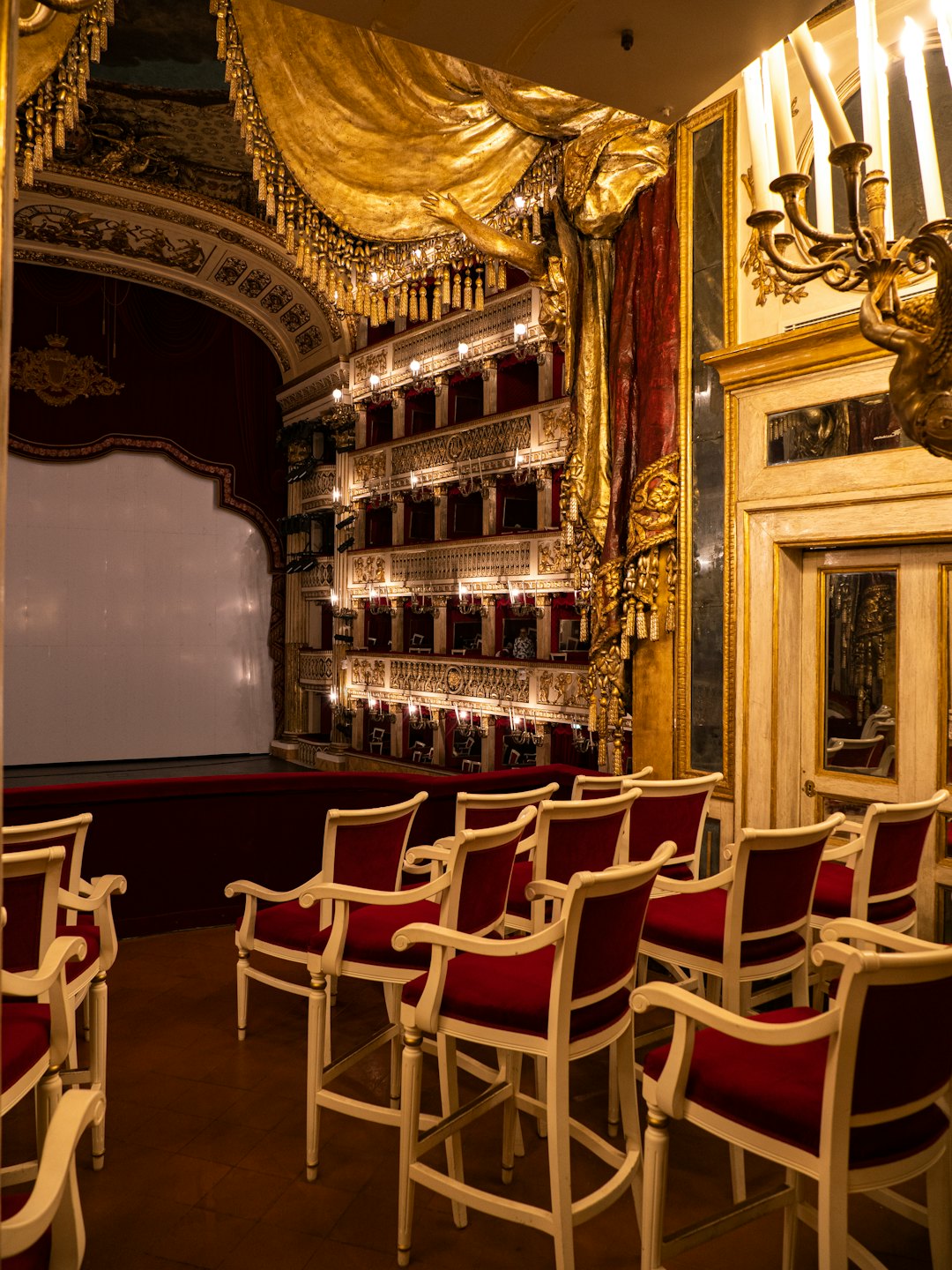 Teatro vuoto con sedie rosse rivolte verso un grande palco.